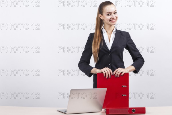 Attractive young caucasian businesswoman with ponytail in black suit stand near the office desk