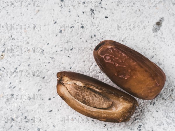 Sweet raw dates on gray cement background. Whole dates and half with bone date on grey concrete