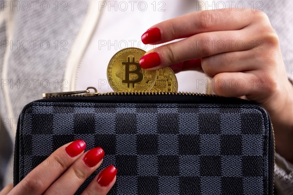 Virtual cryptocurrency money Bitcoin golden coins in the left hand of a woman with red nail polish