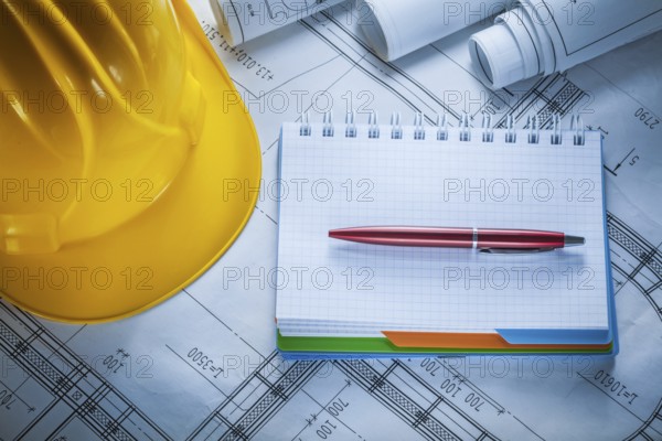 Hard hat checked notebook pen blueprints on construction drawing