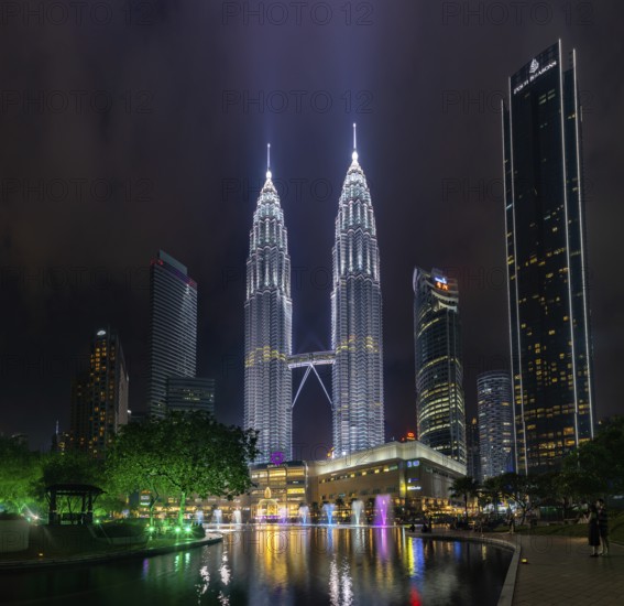 A picture of the Petronas Twin Towers, the KLCC Park water and light fountain show and the Suria
