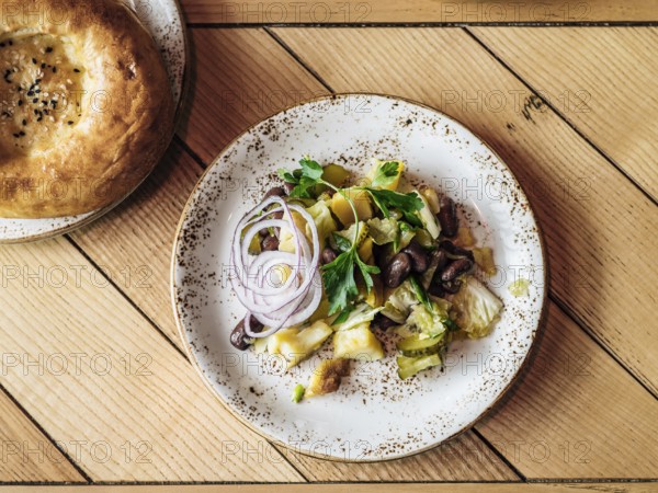 Authentic shot of georgian style salad with red beans, potatoes, salted cucumber on rustic wooden