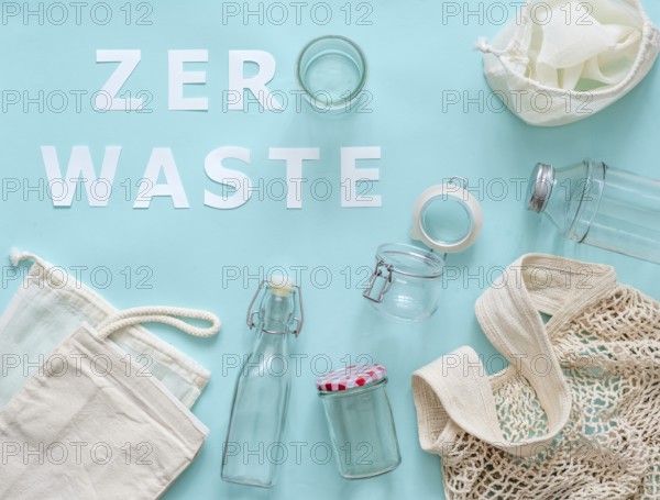 Zero waste concept. Textile eco bags, glass jar and bottle on blue background with Zero Waste white