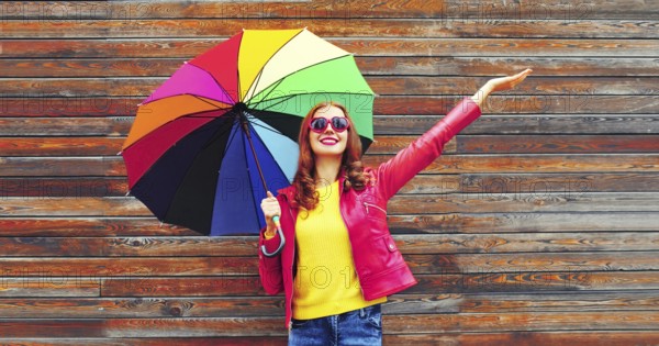 Autumn portrait of happy smiling young woman holding colorful umbrella wearing red jacket, heart