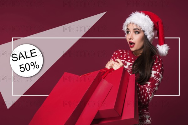 Christmas woman. Beauty model girl in santa hat on red background. Funny laughing surprised woman