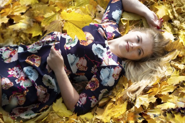 A beautiful girl lies in the autumn leaves
