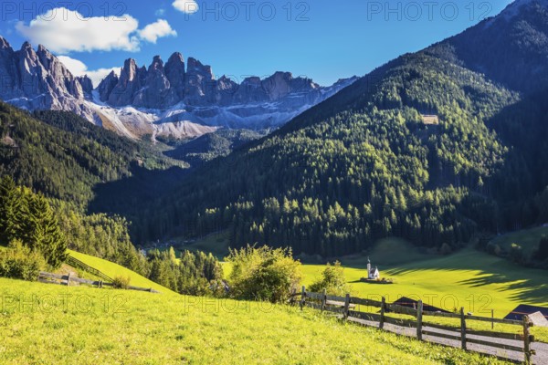 Picturesque little church of Santa Maddalena in valley Val di Funes. Sunny day in Dolomites, Tirol.
