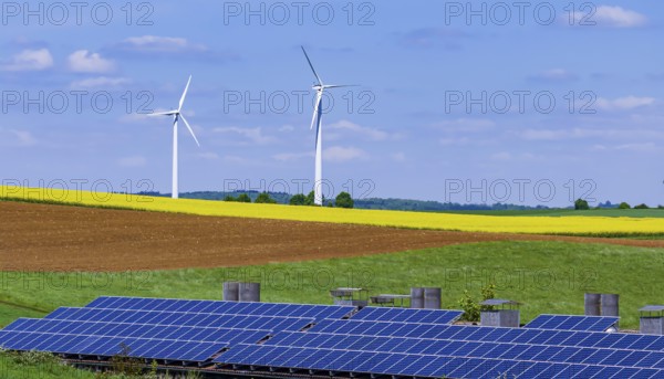 Landscape of the Swabian Alb in spring with rape field and wind turbines. In front of it a building