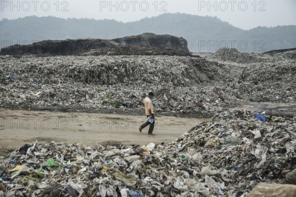 A person walking between garbage heap at a garbage dumpsite in the eve of World Environment Day, in