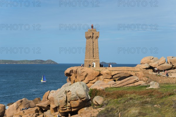 Lighthouse overlooking the rocky coast with sailing boat on the horizon, Phare de Men Ruz,