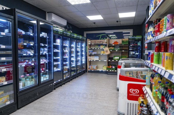 Modern supermarket with illuminated refrigerated shelves and numerous products, Tante M,