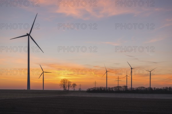Wind farm at sunset, the sky is bathed in soft pink and orange, near Ulm, Swabian Alb,