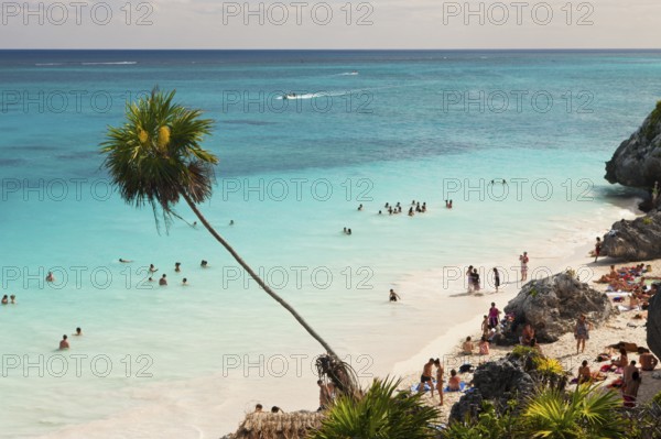 Tourists on the beach in front of the Mayan ruins of Tulum, Riviera Maya, Yucatan Peninsula,