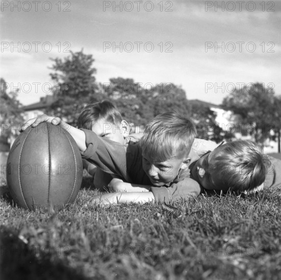 Rugby 1940. Three young rugby players lying in the grass on the rugby field, one holding the rugby