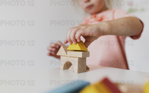 Little child girl playing wooden building blocks at home or kindergarten. Development and