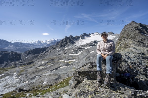 Mountaineer resting on a rock, in rocky mountain landscape, at Col de Prafleuri, Valais Alps, Val