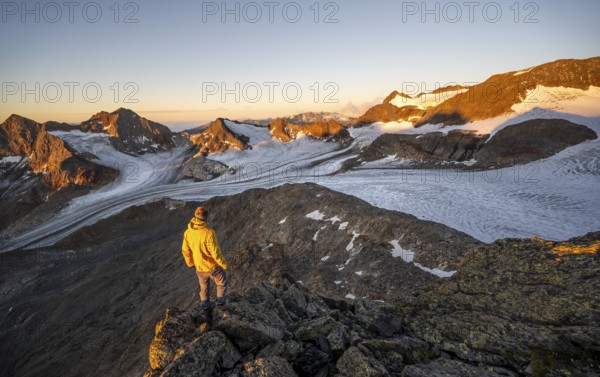 Mountaineers in front of a picturesque high mountain landscape at sunrise with alpenglow, glacier