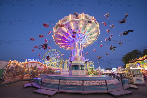 An illuminated chain carousel turns at a fairground at night, chain carousel, spring festival,