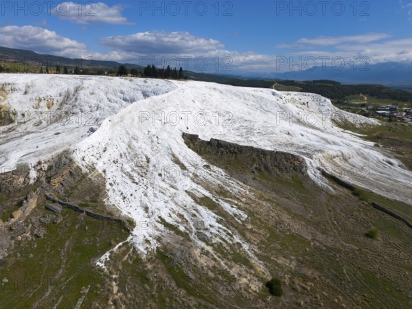 White limestone hills in a natural setting under a blue sky with clouds, aerial view, sinter