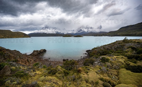 Cloudy mountain range Cuernos del Paine, shore of the blue lake Lago Pehoe in the evening light,