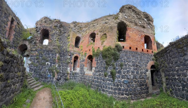 Panoramic photo of interior of northern inner part with partially restored secured masonry of ruins