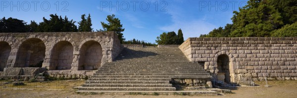 Panorama of a stone staircase and ancient structures with trees in the background, open staircase
