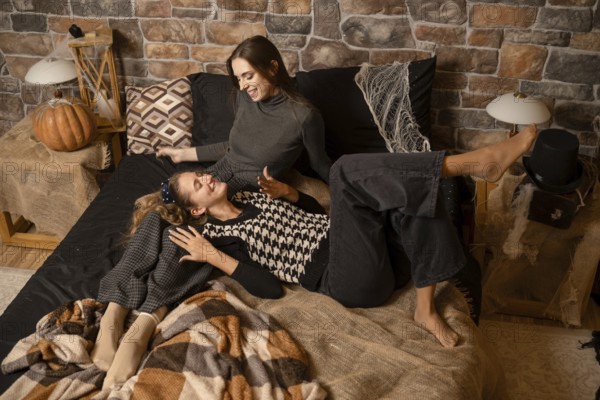 Two friends relax on a cozy bed, enjoying each others company. The warm atmosphere features autumn