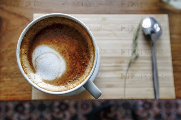 Cup of coffee with milk foam, cappuccino, coffee speciality on a wooden board, view from above,