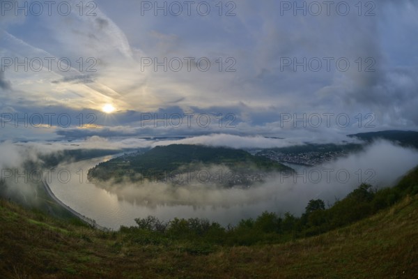 River landscape in a bend with misty hills and cloudy sky illuminated by the sunrise, summer, Rhine