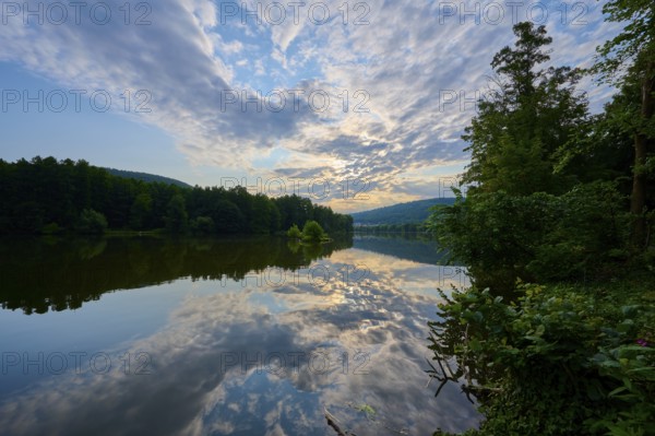 An impressive sky with clouds over a quiet, reflecting river at sunrise, summer, Grünenwört,