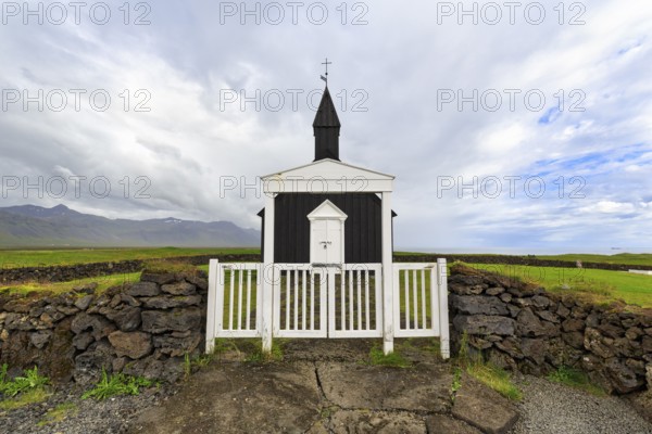Traditional black church with white wooden door and stone wall, wooden church Budakirkja, Búðir,