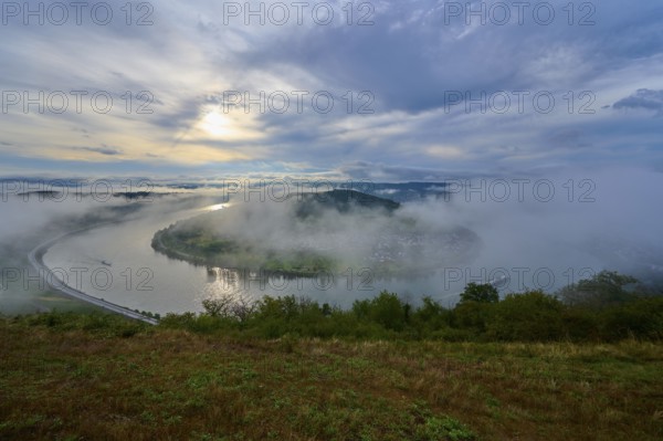 River landscape with wafts of mist and rolling hills in the background. Calm atmosphere, summer,