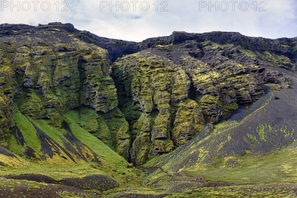 Moss-covered rock formation with entrance to the mystical lava cave, Sönghellir lava tube, Cave of