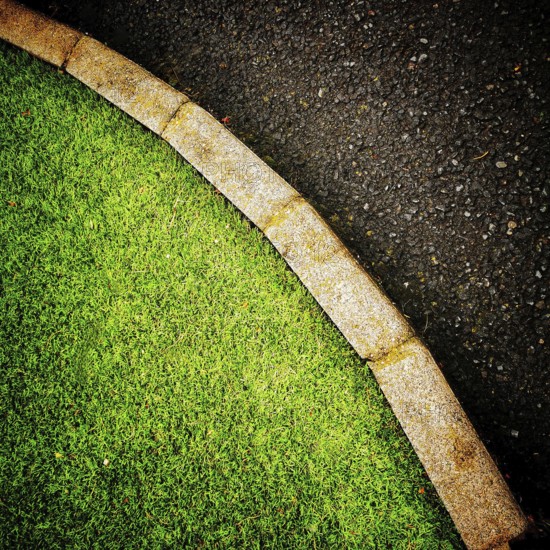 The vibrant green grass curves smoothly alongside a dark asphalt pathway, creating a pleasing
