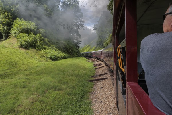 Steam from the Great Smoky Mountains Railroad hangs in the air as the train rounds a curve through