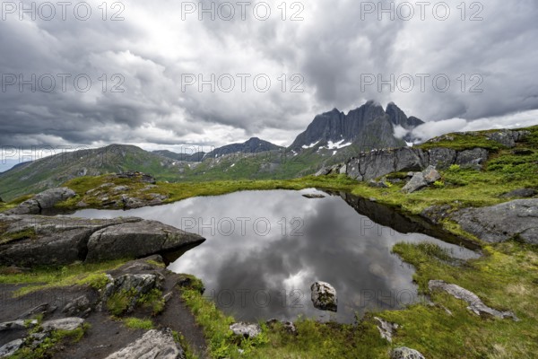 Small lake in mountain landscape, hike to Barden mountain, Breidtind mountain peak behind, Senja,