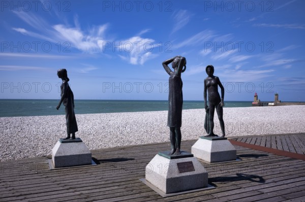 Bronze sculpture La Heure du Bain by Dominique Denry on the beach, sky, blue, behind it beacon Feu