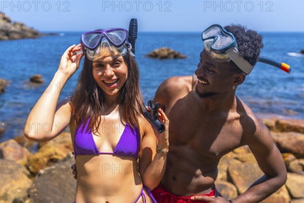 Young couple smiling and wearing snorkeling masks at the beach, eagerly preparing for an exciting