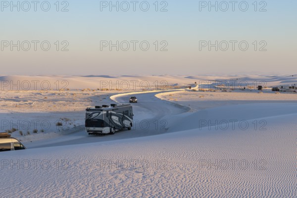 Vehicles being driven on cleared roads through the white gypsum dunes at White Sands National Park