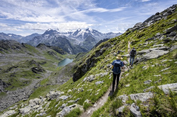 Mountaineer on hiking trail in mountain landscape, descent at Col du Louvie, view of mountain lake
