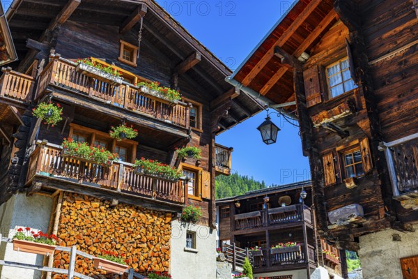 Old wooden houses in log construction, decorated with flowers, historic village centre, Grimentz,
