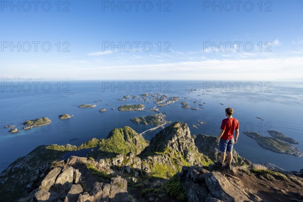 View of numerous small rocky islands with houses, mountaineers on the summit of Festvågtind, view