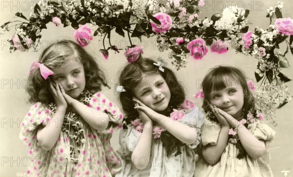 3 girls with flowers, 1900, Three girls in old-fashioned clothes with flowers and pink decorations,