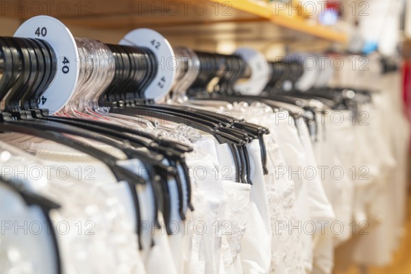 White shirts on hangers with size labels in a shop, focus on the size display, Sindelfingen,