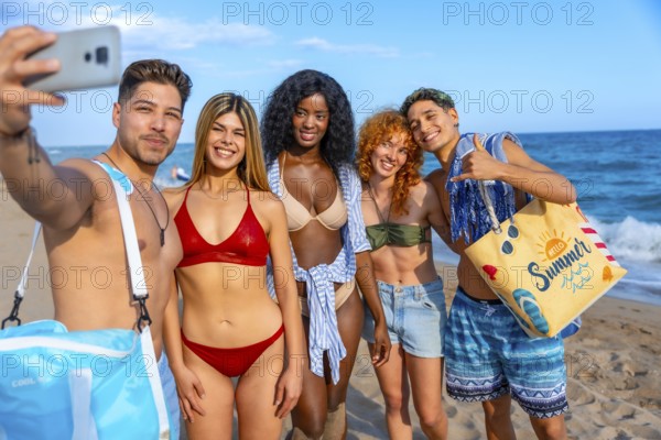 Group of cheerful young multi ethnic friends in swimwear taking selfie on the beach during summer