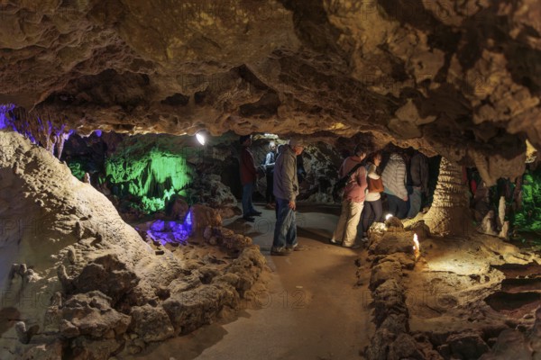Tourists walking past limestone rock formations in a cave at Florida Caverns State Park in the