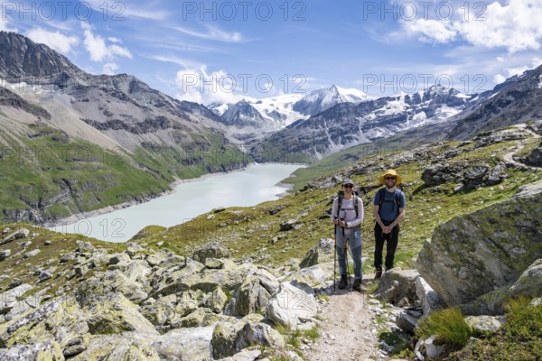 Mountaineer on a hiking trail at a blue mountain lake, reservoir Lac des Dix, behind mountain peak