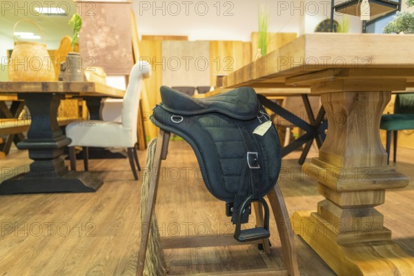 A saddle lies on a wooden chair in a furniture shop, surrounded by rustic woodwork, Sindelfingen,