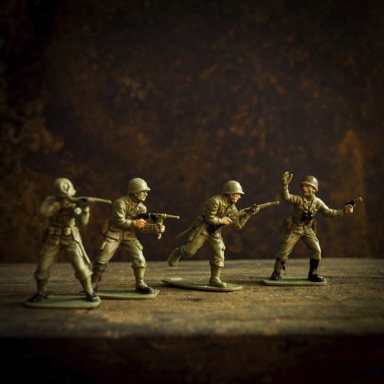 Four toy soldiers stand in various combat stances, ready for action on a weathered wooden surface.