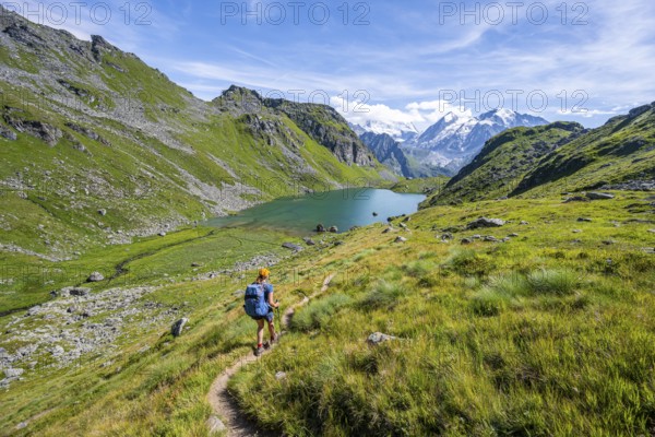 Mountaineer on hiking trail in picturesque mountain landscape, view of mountain lake Lac du Louvie